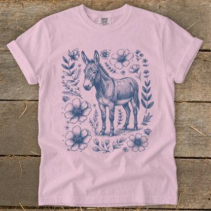 Pink t-shirt with a charcoal sketch of a donkey surrounded by flowers.
