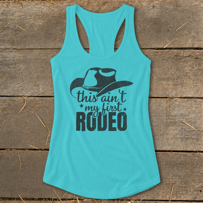 Turquoise tank top with black cowboy hat graphic and text "this ain't my first RODEO".