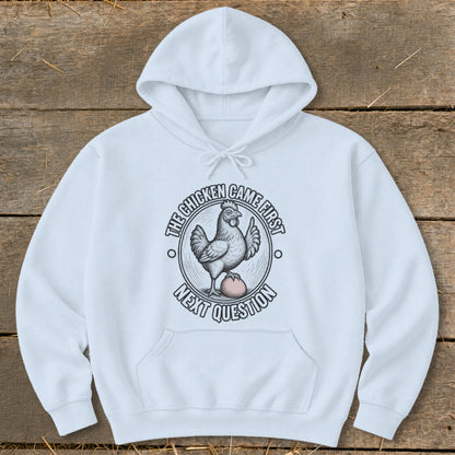 White hoodie with graphic of a chicken on an egg, reading "The chicken came first, next question."