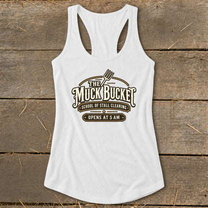 White tank top with "The Muck Bucket School of Stall Cleaning Opens at 5 AM" logo.