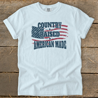 White t-shirt with distressed American flag graphic: "COUNTRY RAISED AMERICAN MADE".