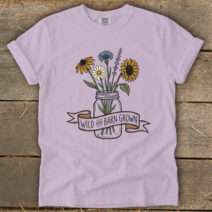 Light purple t-shirt with a mason jar of wildflowers and banner reading "WILD AND BARN GROWN."