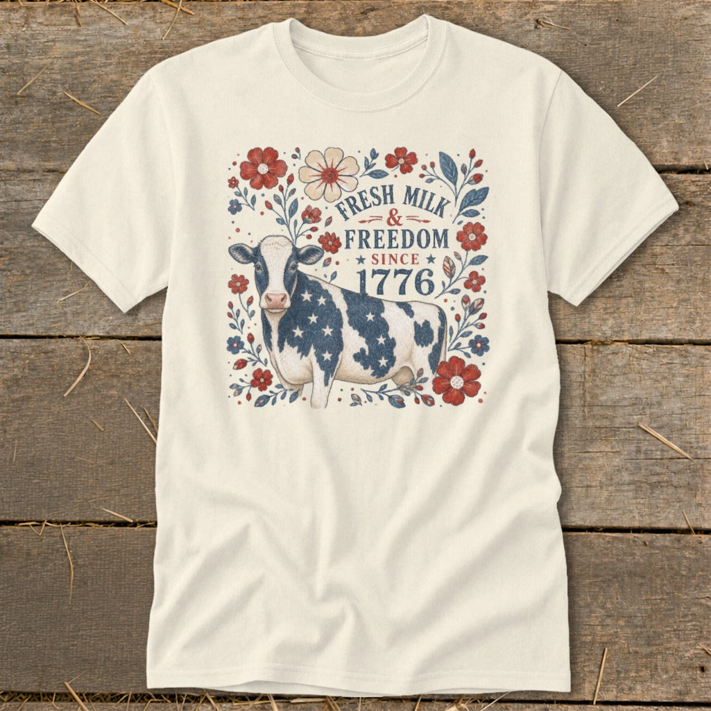 Cream t-shirt with patriotic cow, flowers, and text "Fresh Milk & Freedom Since 1776".