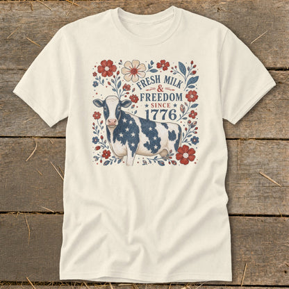 Cream t-shirt with patriotic cow, flowers, and text "Fresh Milk & Freedom Since 1776".