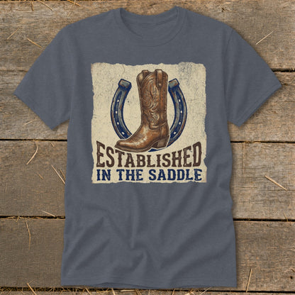 Gray t-shirt with cowboy boot and horseshoes graphic reading "Established in the Saddle".