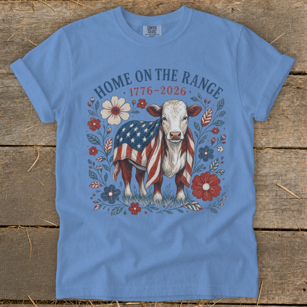Cow wearing American flag blanket surrounded by flowers with text "HOME ON THE RANGE 1776-2026".