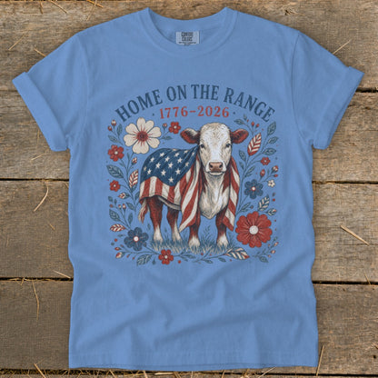 Cow wearing American flag blanket surrounded by flowers with text "HOME ON THE RANGE 1776-2026".