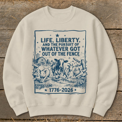 Cream sweatshirt with a blue graphic of farm animals and text "LIFE, LIBERTY, AND THE PURSUIT OF WHATEVER GOT OUT OF THE FENCE 1776-2026".