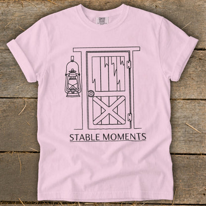 Pink t-shirt with a black line drawing of a barn door and lantern, reading "STABLE MOMENTS".