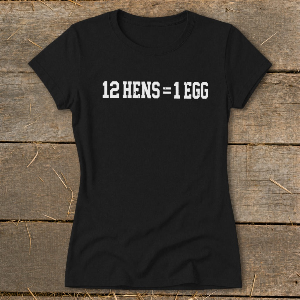Black women's t-shirt printed with the white text 12 HENS = 1 EGG, displayed on wooden planks.