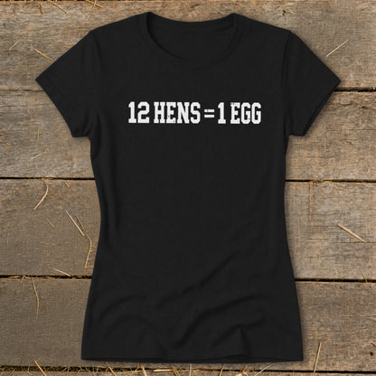 Black women's t-shirt printed with the white text 12 HENS = 1 EGG, displayed on wooden planks.