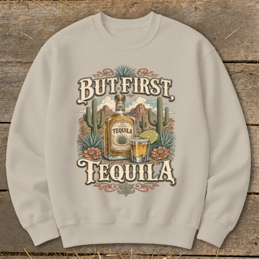 Sweatshirt with "But First Tequila" text, agave bottle, shot glass, lime, and desert landscape.