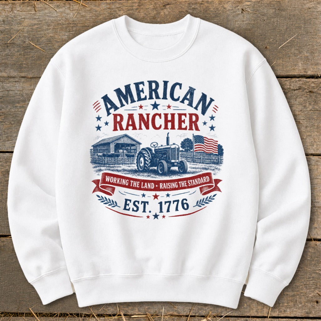 White sweatshirt with "American Rancher" graphic, tractor, barn, and American flag.