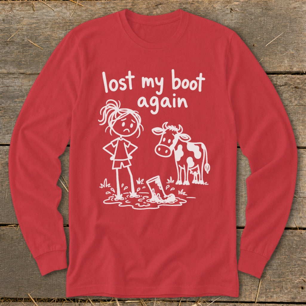 Red long-sleeved t-shirt featuring white text that reads lost my boot again and a cartoon of a girl and cow standing near a muddy boot.