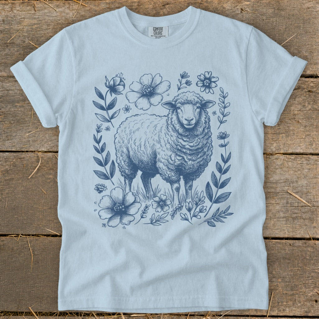 Light blue t-shirt with a detailed blue line drawing of a sheep surrounded by flowers.