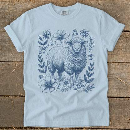 Light blue t-shirt with a detailed blue line drawing of a sheep surrounded by flowers.