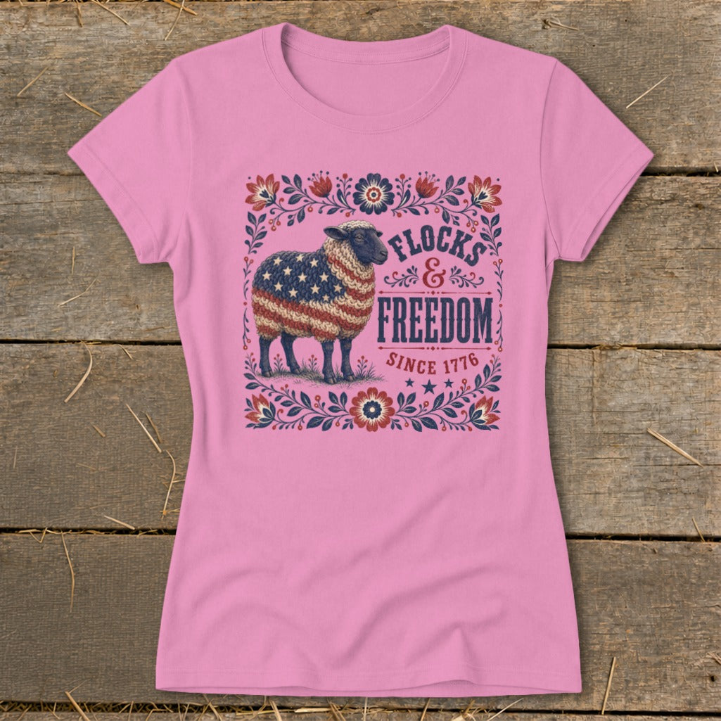 Pink t-shirt with a sheep adorned in the American flag and the words "Flocks & Freedom Since 1776".