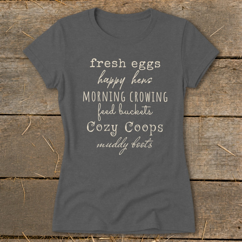 Dark grey t-shirt with white text: "fresh eggs happy hens MORNING CROWING feed buckets Cozy Coops muddy boots".