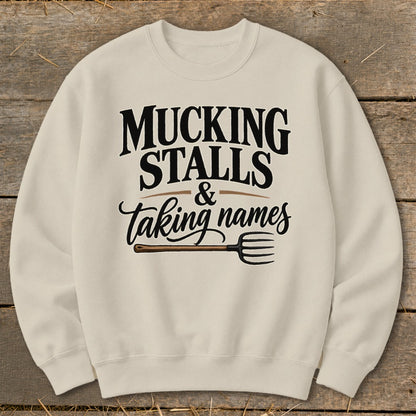 Cream sweatshirt with "MUCKING STALLS & taking names" text and a pitchfork graphic.