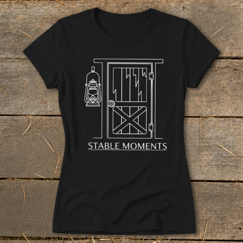 Black t-shirt with white line art of a barn door and hanging lantern, with text "STABLE MOMENTS".