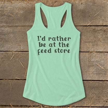 Light green racerback tank top with black text reading "I'd rather be at the feed store."