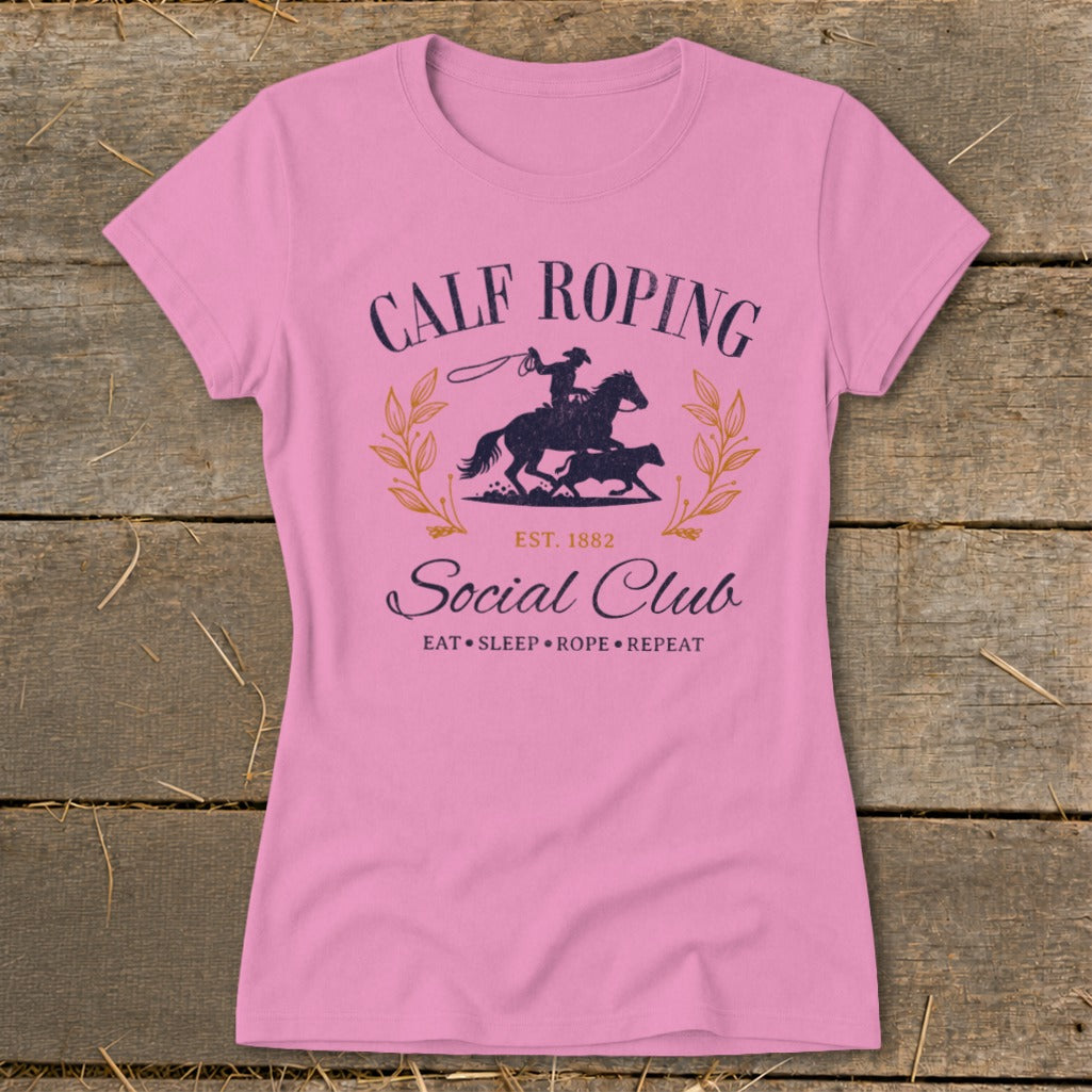 Pink t-shirt with "Calf Roping Social Club" graphic featuring a cowboy on a horse roping a calf.