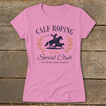 Pink t-shirt with "Calf Roping Social Club" graphic featuring a cowboy on a horse roping a calf.