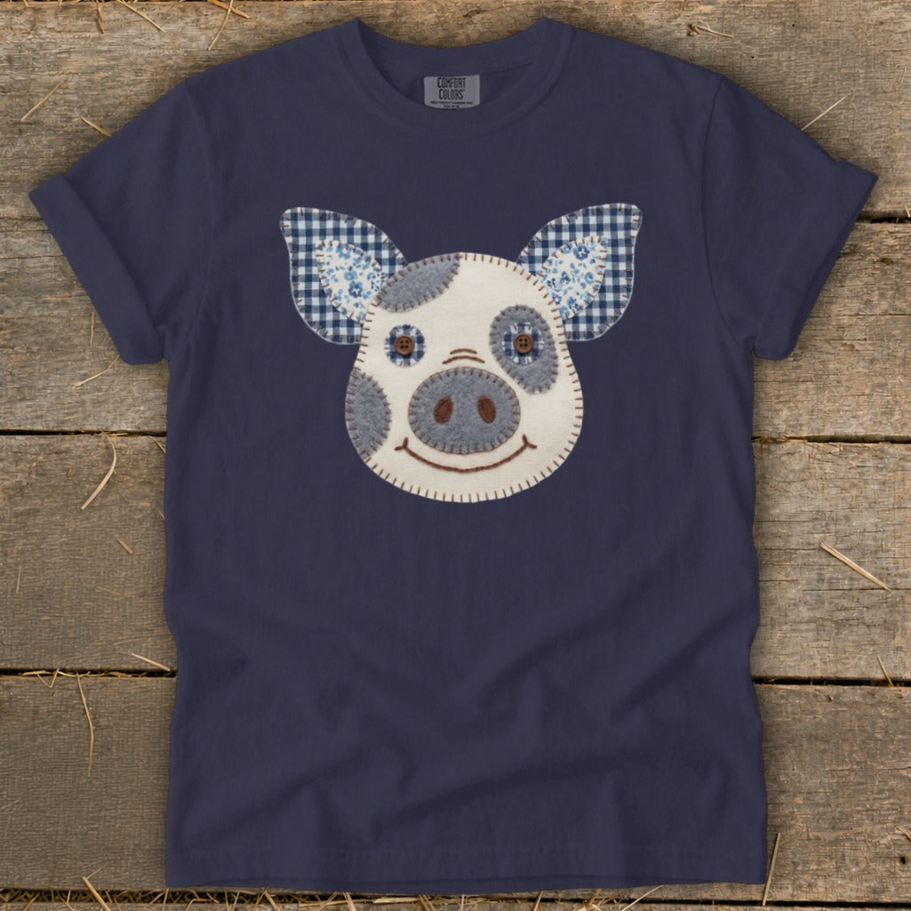 Navy t-shirt with a patchwork pig face appliqué and blue gingham ears.
