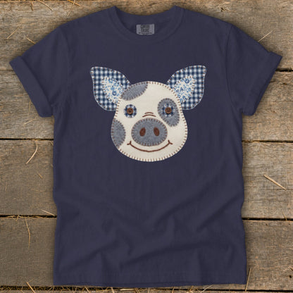Navy t-shirt with a patchwork pig face appliqué and blue gingham ears.