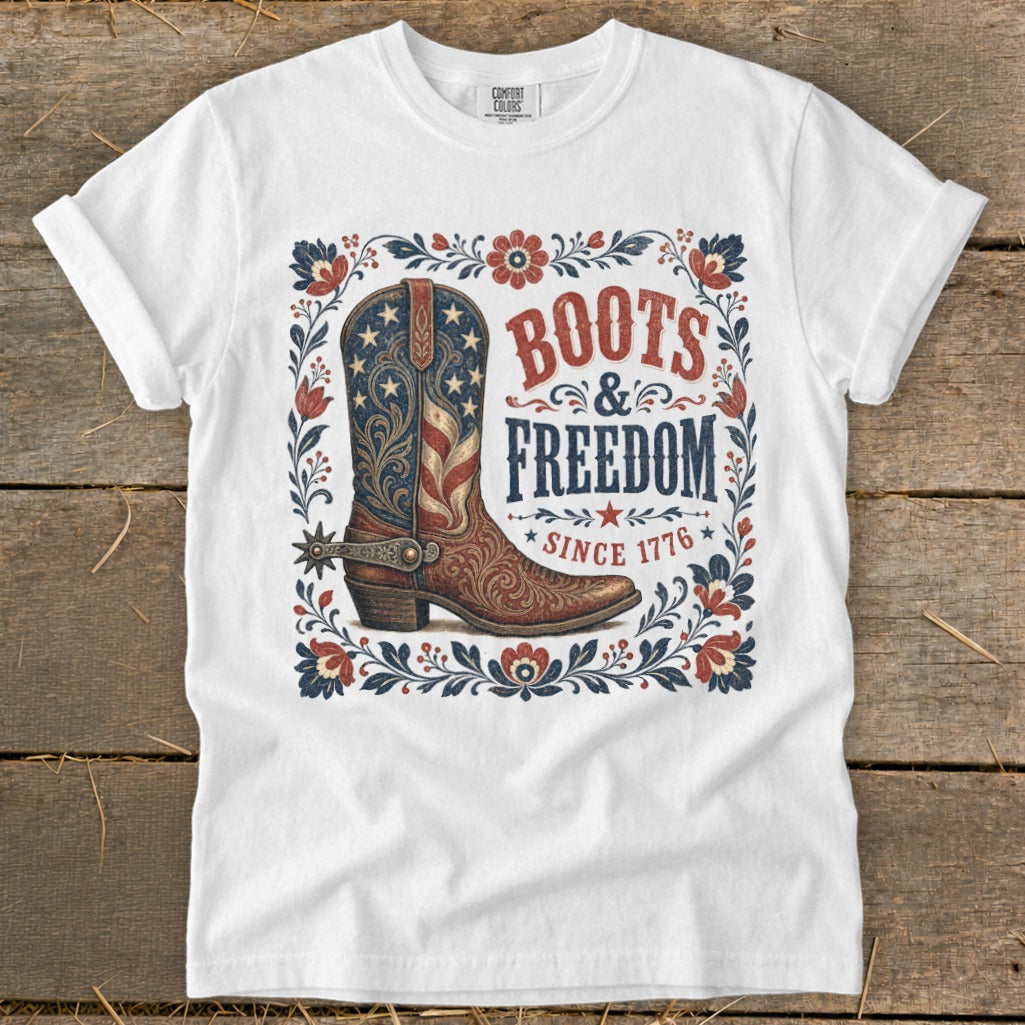 White t-shirt with American flag boot, "Boots & Freedom Since 1776" text, floral border.