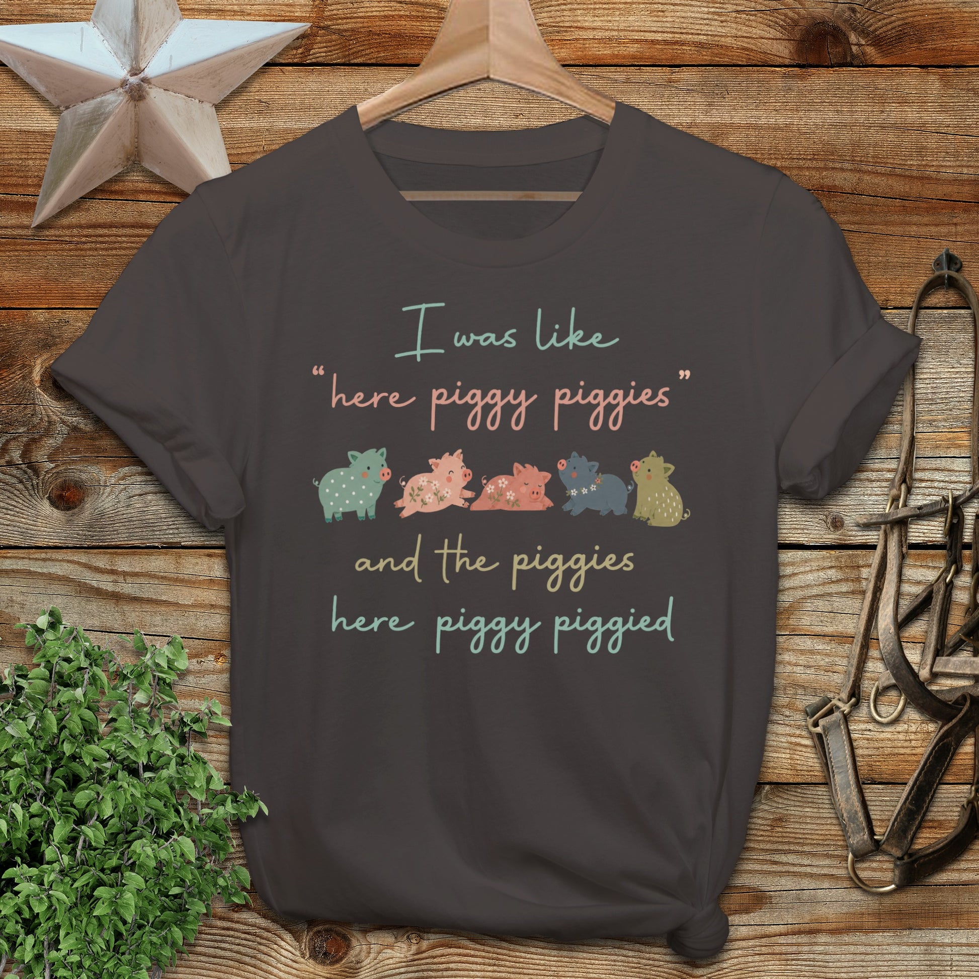 Dark t-shirt with "I was like 'here piggy piggies' and the piggies here piggy piggied" text and cartoon pigs.