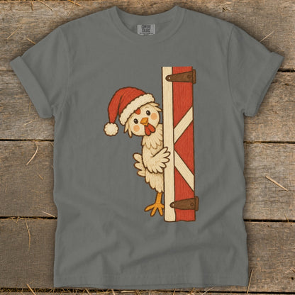 Chicken in Santa hat peeking from behind a red barn door.