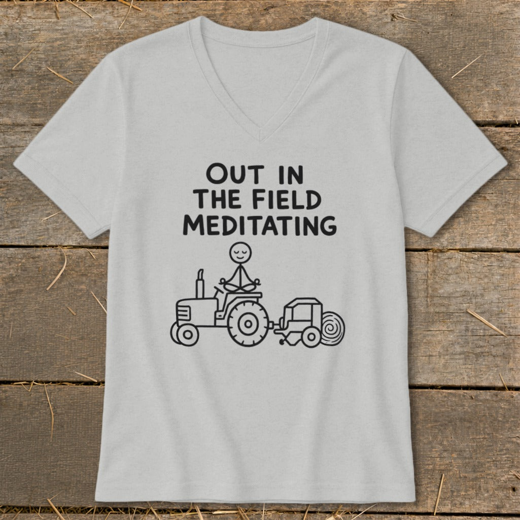Light gray t-shirt with black text "OUT IN THE FIELD MEDITATING" and a stick figure meditating on a tractor.