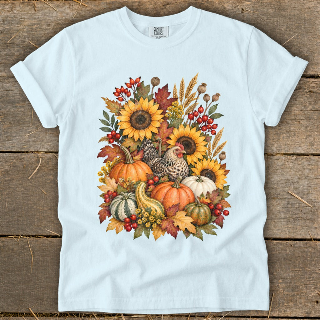 Light blue t-shirt with a watercolor fall harvest design featuring pumpkins, sunflowers, and a chicken.