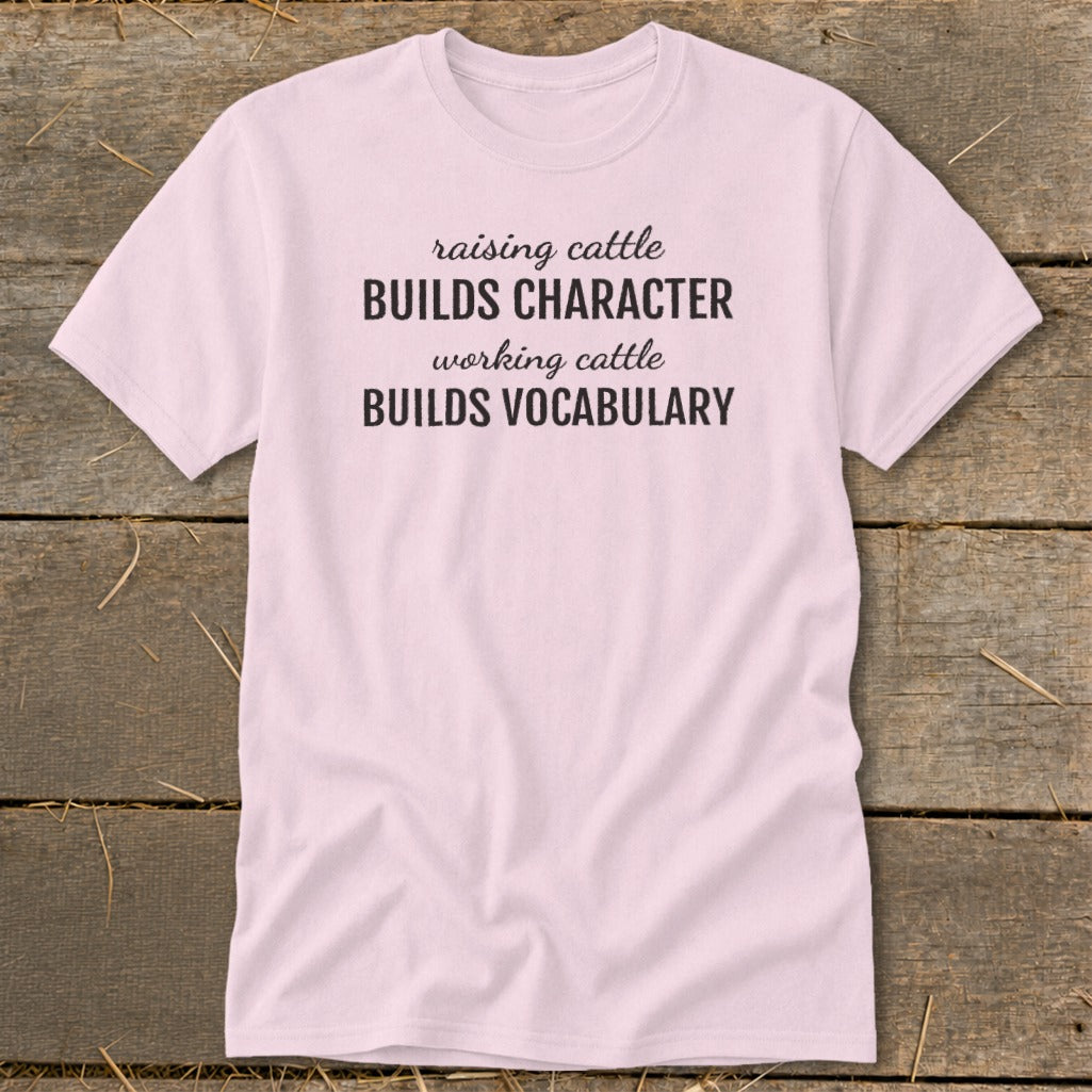 Pink t-shirt with text: "raising cattle BUILDS CHARACTER working cattle BUILDS VOCABULARY"