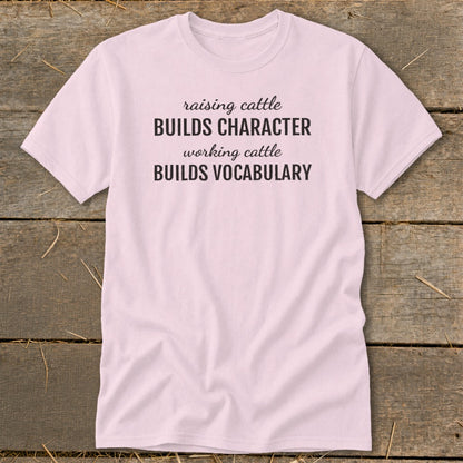 Pink t-shirt with text: "raising cattle BUILDS CHARACTER working cattle BUILDS VOCABULARY"