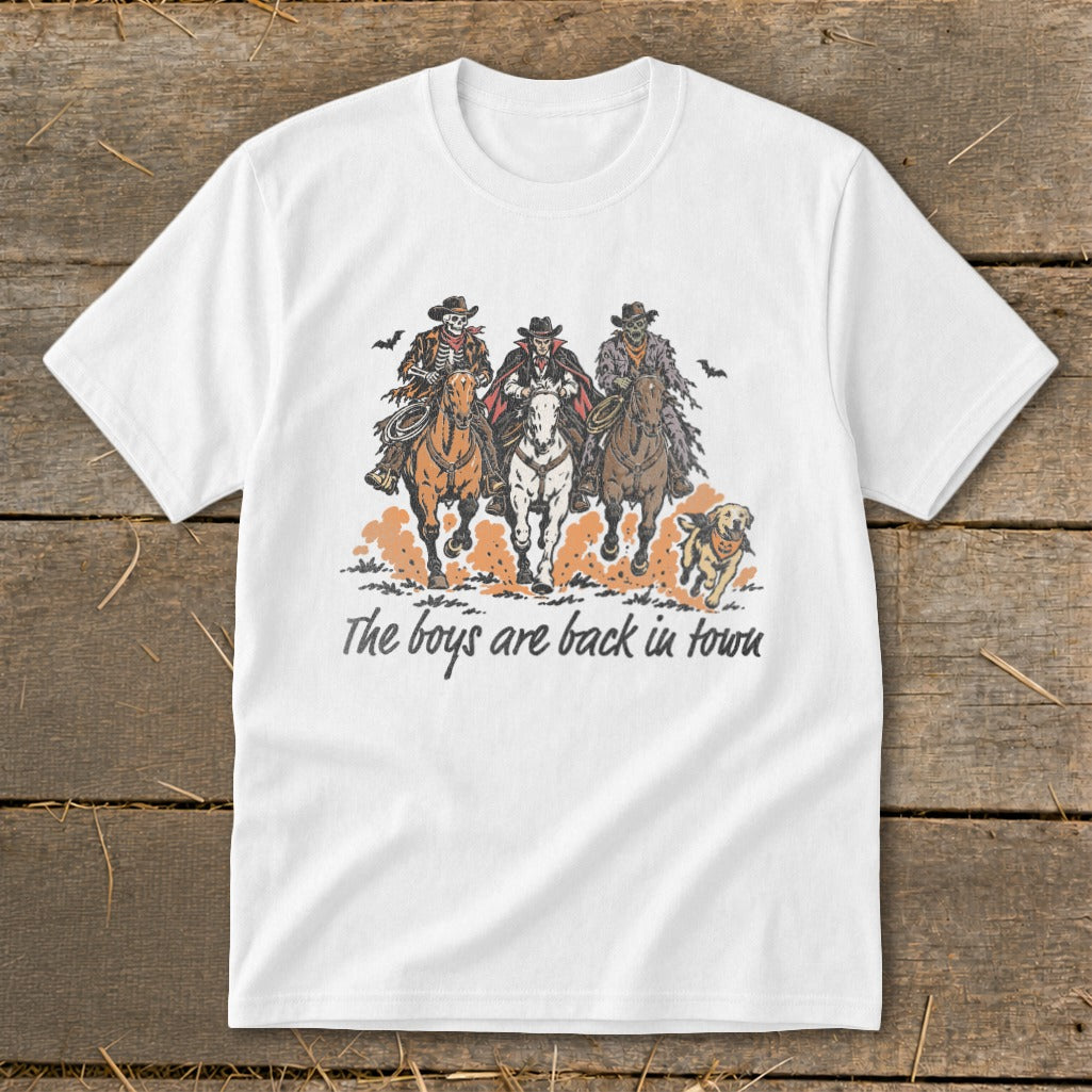 White t-shirt featuring skeleton cowboys and a dog with text "The boys are back in town".