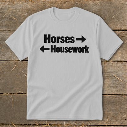 A light gray crewneck t-shirt featuring the black text Horses with a right-pointing arrow and Housework with a left-pointing arrow.