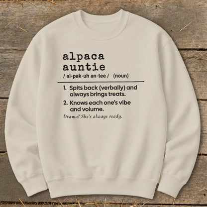 A cream-colored crewneck sweatshirt printed with black text defining the term alpaca auntie.