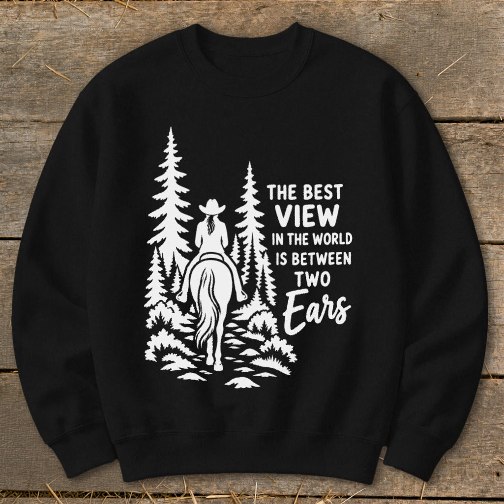 A black crewneck sweatshirt features a white graphic of a horseback rider in a forest with the text The Best View in the World Is Between Two Ears.