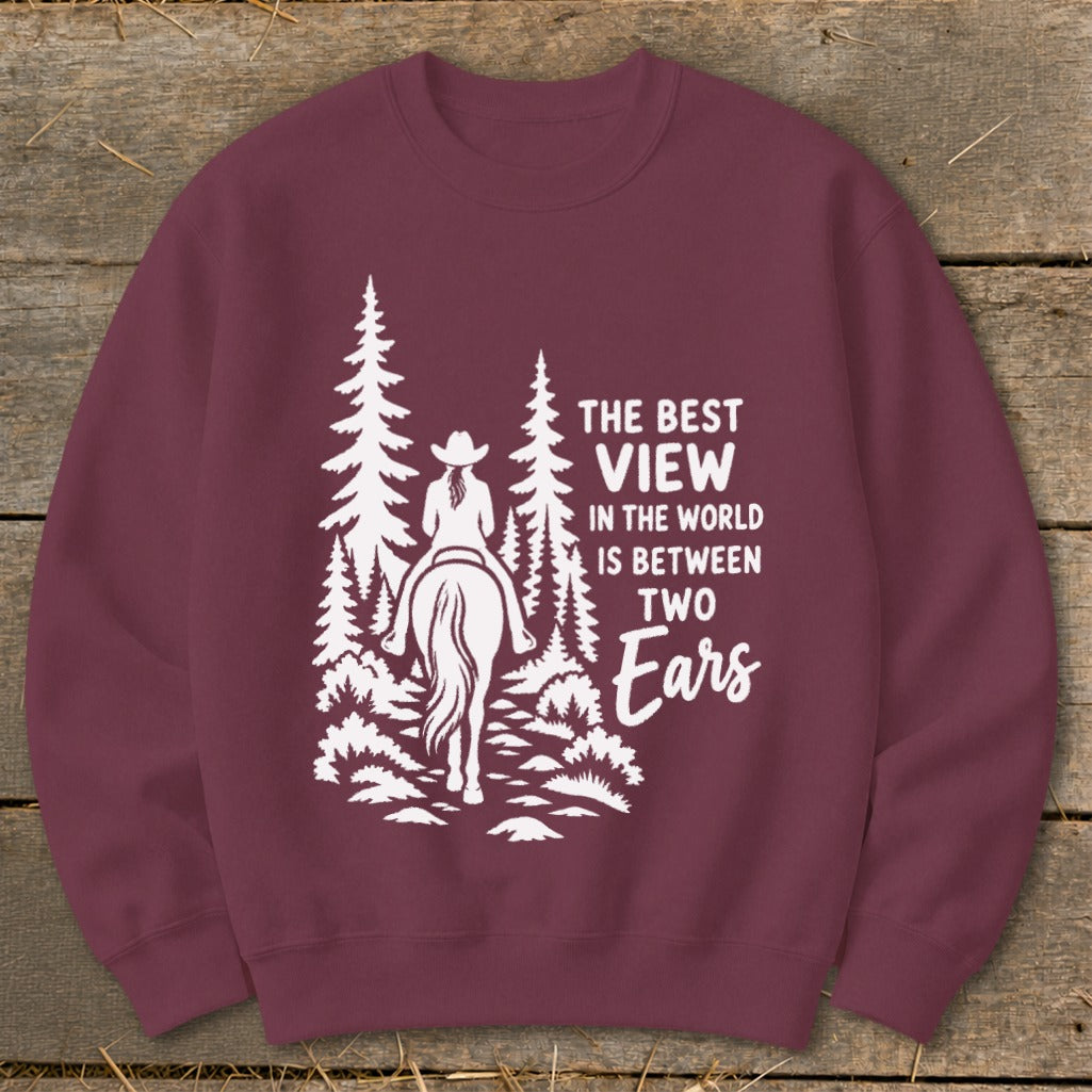 Maroon crewneck sweatshirt with a white graphic of a horseback rider in the woods and the text The Best View in the World is Between Two Ears.