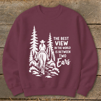 Maroon crewneck sweatshirt with a white graphic of a horseback rider in the woods and the text The Best View in the World is Between Two Ears.