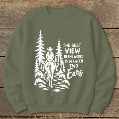 Olive green crewneck sweatshirt featuring a white graphic of a horseback rider among pine trees with the text The Best View in the World Is Between Two Ears.