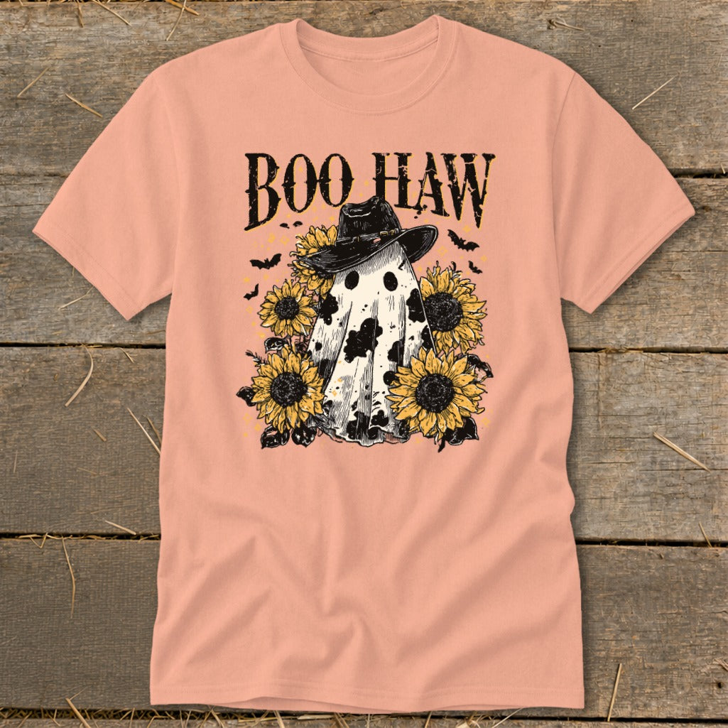 A peach crewneck t-shirt featuring a cow-print ghost in a cowboy hat surrounded by sunflowers and bats, with the text BOO HAW above.