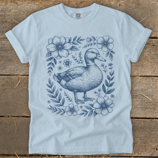 Light blue t-shirt with a blue sketch of a duck surrounded by flowers.