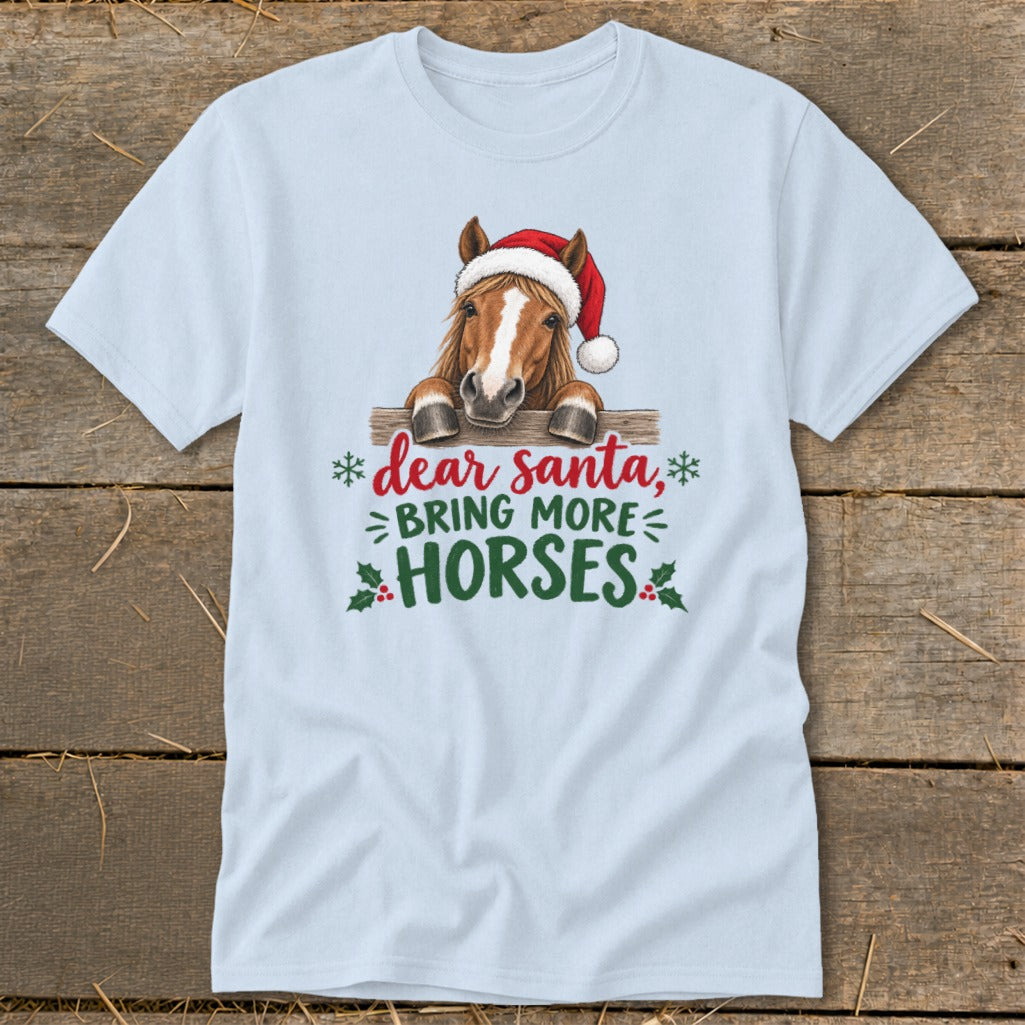 Light blue t-shirt featuring a graphic of a horse wearing a Santa hat behind a fence, with the text Dear Santa, bring more horses.