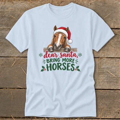 Light blue t-shirt featuring a graphic of a horse wearing a Santa hat behind a fence, with the text Dear Santa, bring more horses.