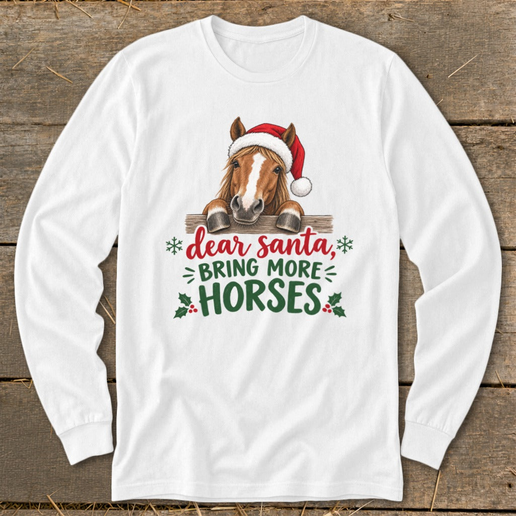 A white long-sleeved t-shirt features a graphic of a horse wearing a Santa hat behind a wooden fence with the text "dear santa, bring more horses".