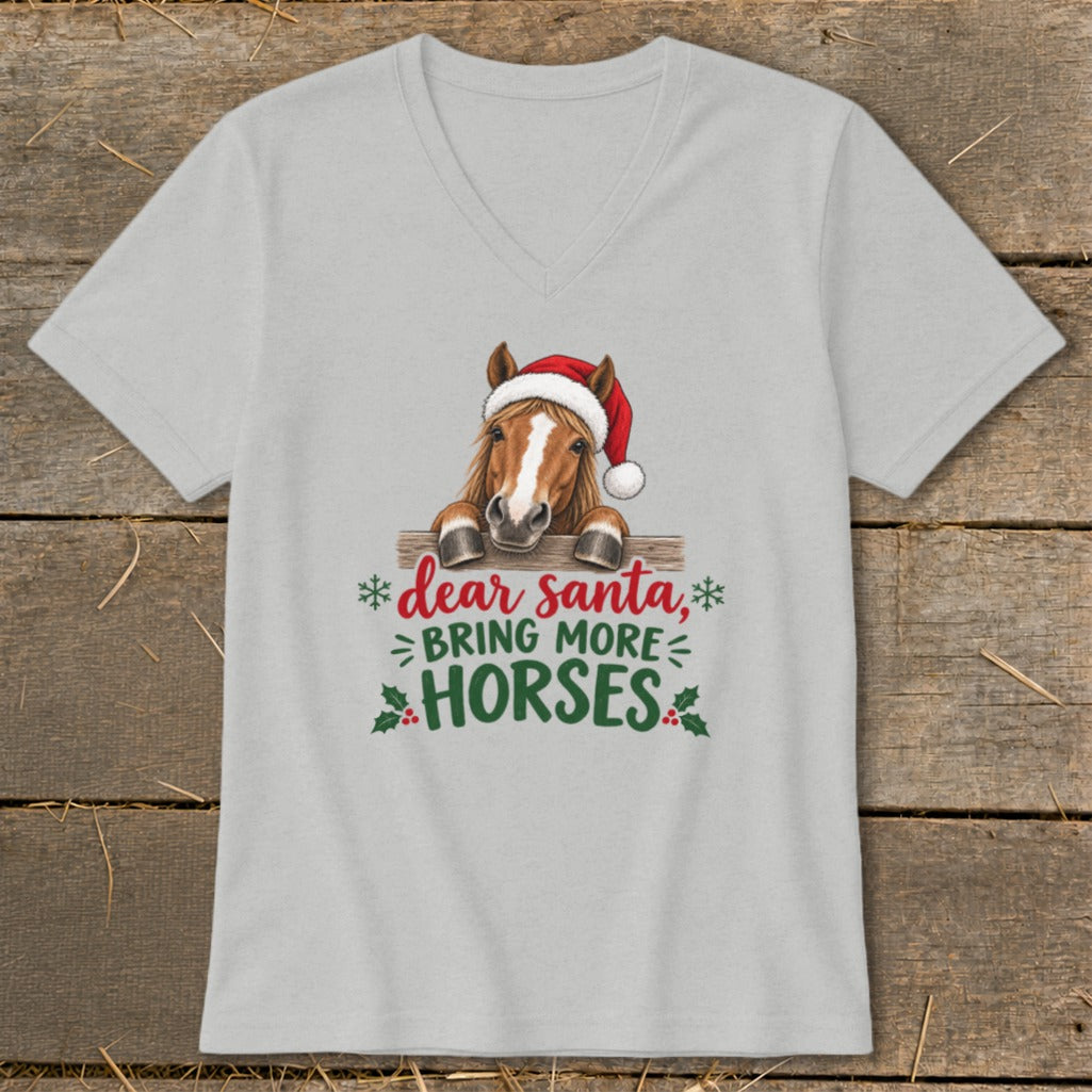 A light gray V-neck T-shirt featuring a graphic of a horse wearing a Santa hat behind a fence with the text "dear santa, bring more horses".