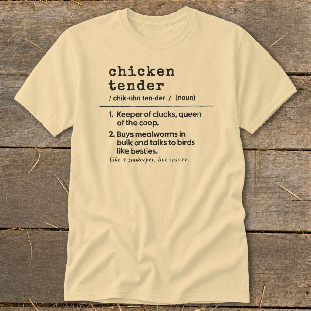 A cream-colored t-shirt on a wooden background with black text defining the term chicken tender.